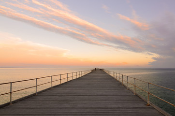 Fototapeta na wymiar Wooden jetty at dusk with clouds in the sky