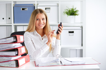 Smiling business woman calculates tax at desk in office