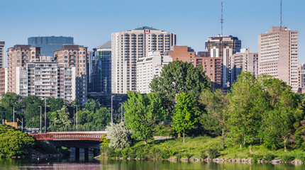 Ottawa River and capitol city skyline along the parkway - late springtime afternoon - early evening approaches.  Tall buildings, apartments and condominiums comprise an Ottawa city skyline. - obrazy, fototapety, plakaty