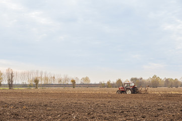 Red Tractor Plowing in Autumn