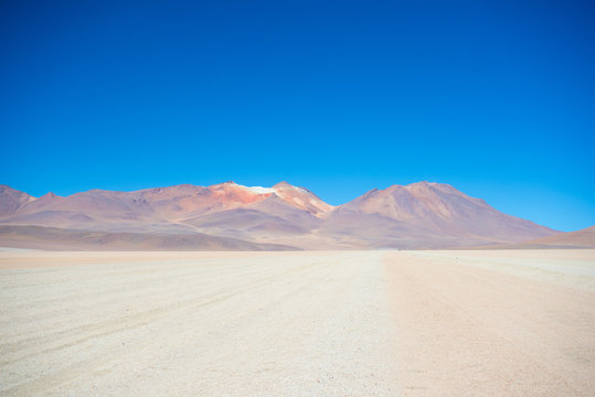 Sandy desert stretch and volcano on the Bolivian Andes