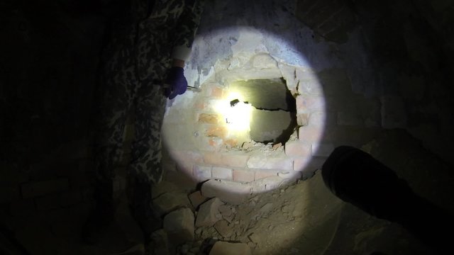 Человек в подвале разбивает кирпичную стену