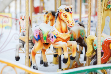 Fairground carousel horses during the day covered with snow in winter city park entertainment.  © maynagashev