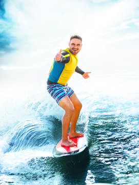 Surfing, blue ocean. Young Man show thumbs up on wakeboard. 