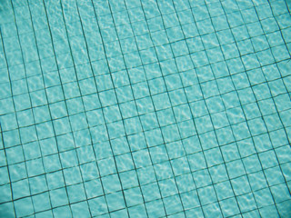 light reflection on water surface of swimming pool with turquoise color tiles on the bottom