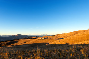 Plateau of Lessinia and Italian Alps / Plateau of Lessinia at sunset, Regional Natural Park of Lessinia, Veneto, Verona, Italy. In the background the Italian Alps