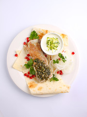 roasted meat with pita pomegranate and onion on a white plate
