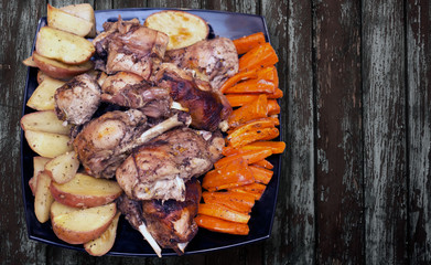 Roasted rabbit on a black plate with the vegetables