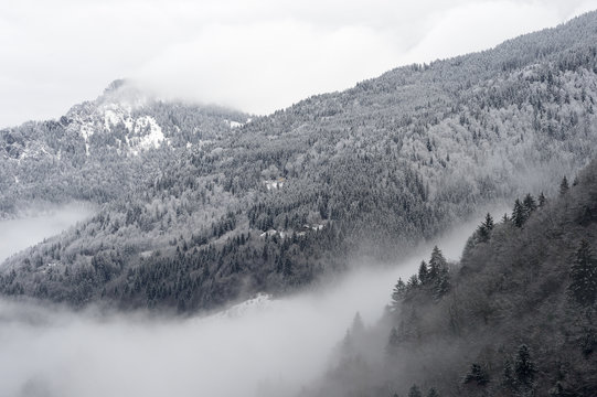 Mountain valley with snow and low clouds.