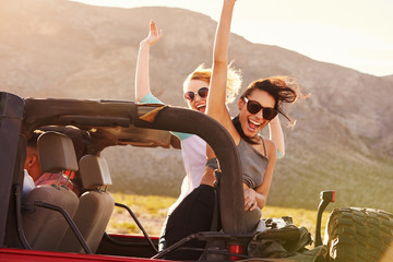 Obraz premium Friends On Road Trip Driving In Convertible Car