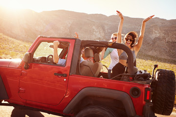 Friends On Road Trip Driving In Convertible Car