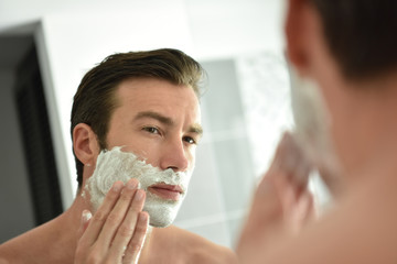 Adult man shaving with foam and manual razer