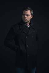 Obraz premium Stubbly bearded young man wearing dark blue winter coat.