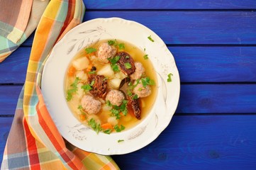Meatball soup with sundried tomatoes on deep blue wooden table