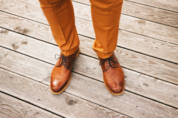 male legs in brown shoes on a wooden floor
