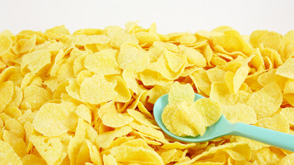 The close up of tasty golden corn flakes with the green plastic spoon.