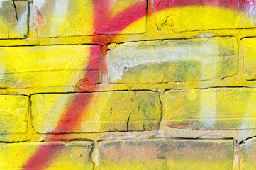 Detail of a red and yellow graffiti on a brick wall