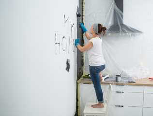 Woman paint wall at home.

