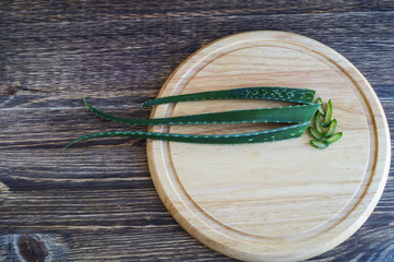 Aloe vera fresh leaf on the cutting board, on wooden background.