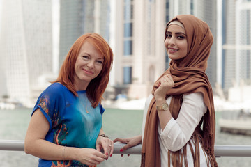 Smiling girl in hijab covering her eyes with happiness in Dubai Marina