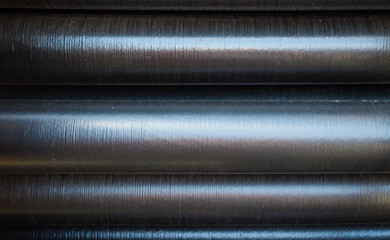 Stacked pipe industrial texture background with light reflecting on central part