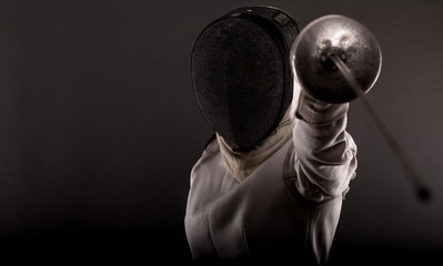 Portrait of woman wearing white fencing costume practicing with the sword.