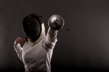 Portrait of woman wearing white fencing costume practicing with the sword.