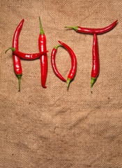Word hot written from red pepper letters on rustic background
