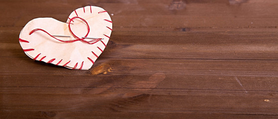 The heart which is cut out from paper and sewed by a red thread