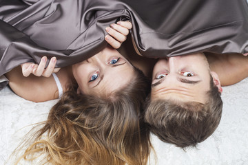 Frightened young couple under the sheets - shock concept