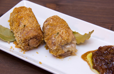 Breaded meat rolls on the tray on wooden table seen up close