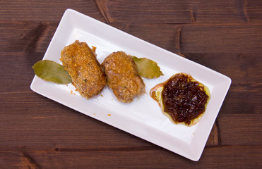 Breaded meat rolls on the tray on wooden table seen from above