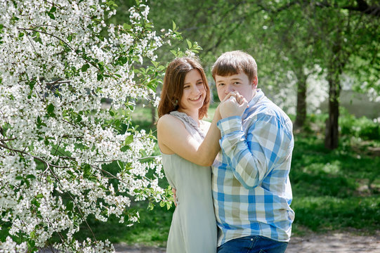 young man kissing a woman's hand in the blossoming spring garden