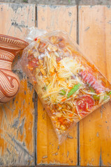 papaya salad in plastic bag on wood table