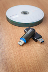 USB flash drives and stacked CDs isolate on wooden background.