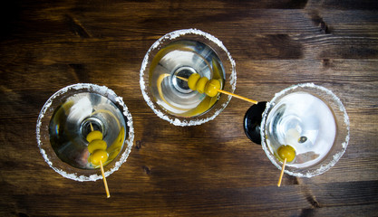 Three Martini with olives on a wooden table.