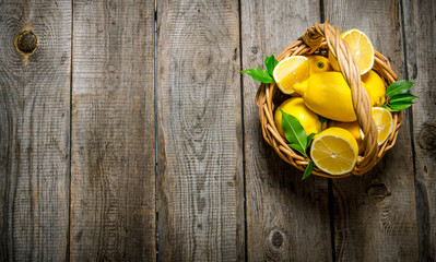 Fresh lemons in a basket with leaves .