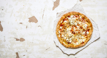 Cheese pizza on a paper. On rustic background.