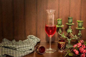 Still life image of red wine and candlestick over wooden backgro