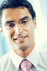 Portrait of young successful smiling businessman at office