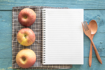 Recipe book with apple  on wooden background