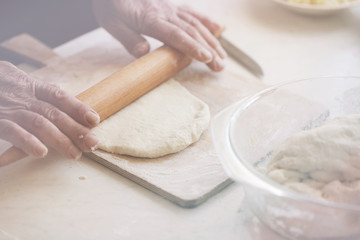 Hands roll the dough on a wooden board