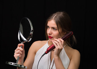 Woman with a mirror and flat hair iron