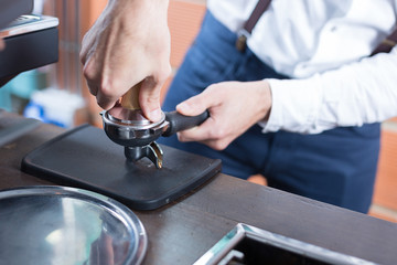 Close-up of man's hands pressing coffee in holder