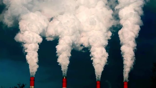 Dramatic view of smoke or steam columns from four red stacks on dark blue background. Dioxide carbon and warm, exhausting with the industry chimneys in the atmosphere, is the great danger for ecology.