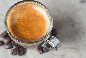 Shot of Espresso with beans on wood