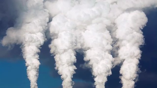 Dramatic view of smoke or steam columns from four stacks on blue background. Dioxide carbon and warm, exhausting with the industry chimneys in atmosphere, is the great danger for global ecology.