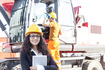 young female engineer posing in junkyard with a worker
