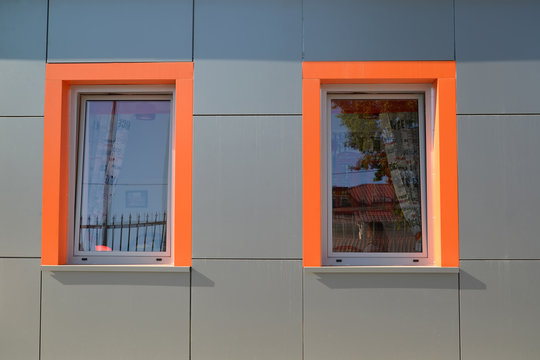 Two windows with orange frames on a gray wall of the building