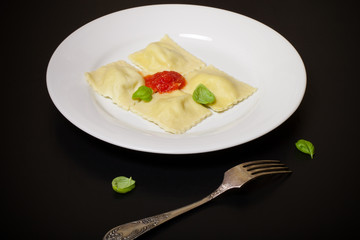 Russian ravioli - pelmeni with tomato sauce and basil on a white